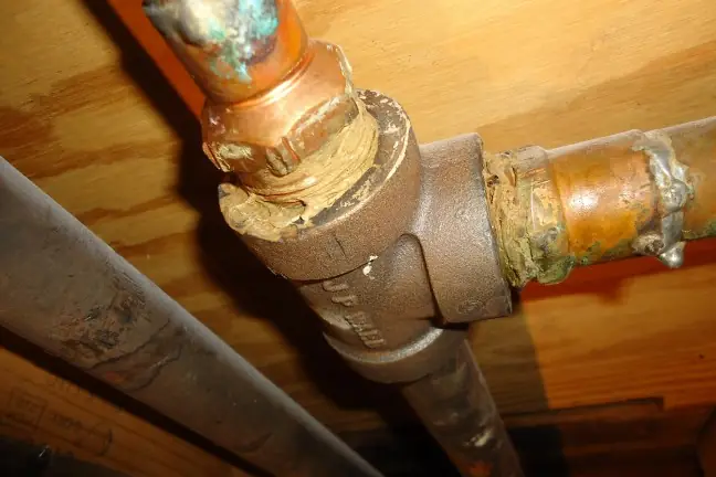 A corroded old pipe joint patched with sealing compound and wrap